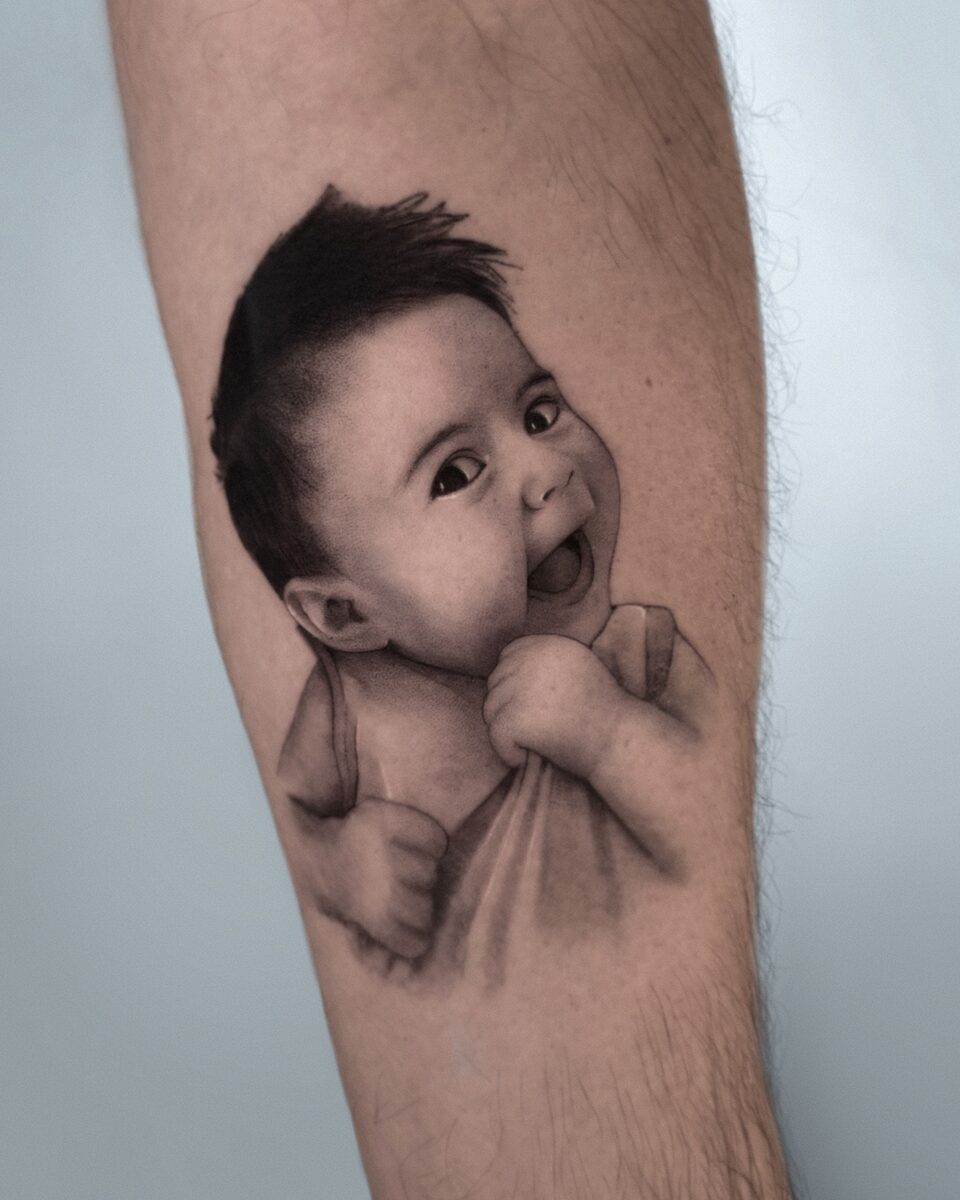 Retrato microrealista de bebé sonriente en antebrazo